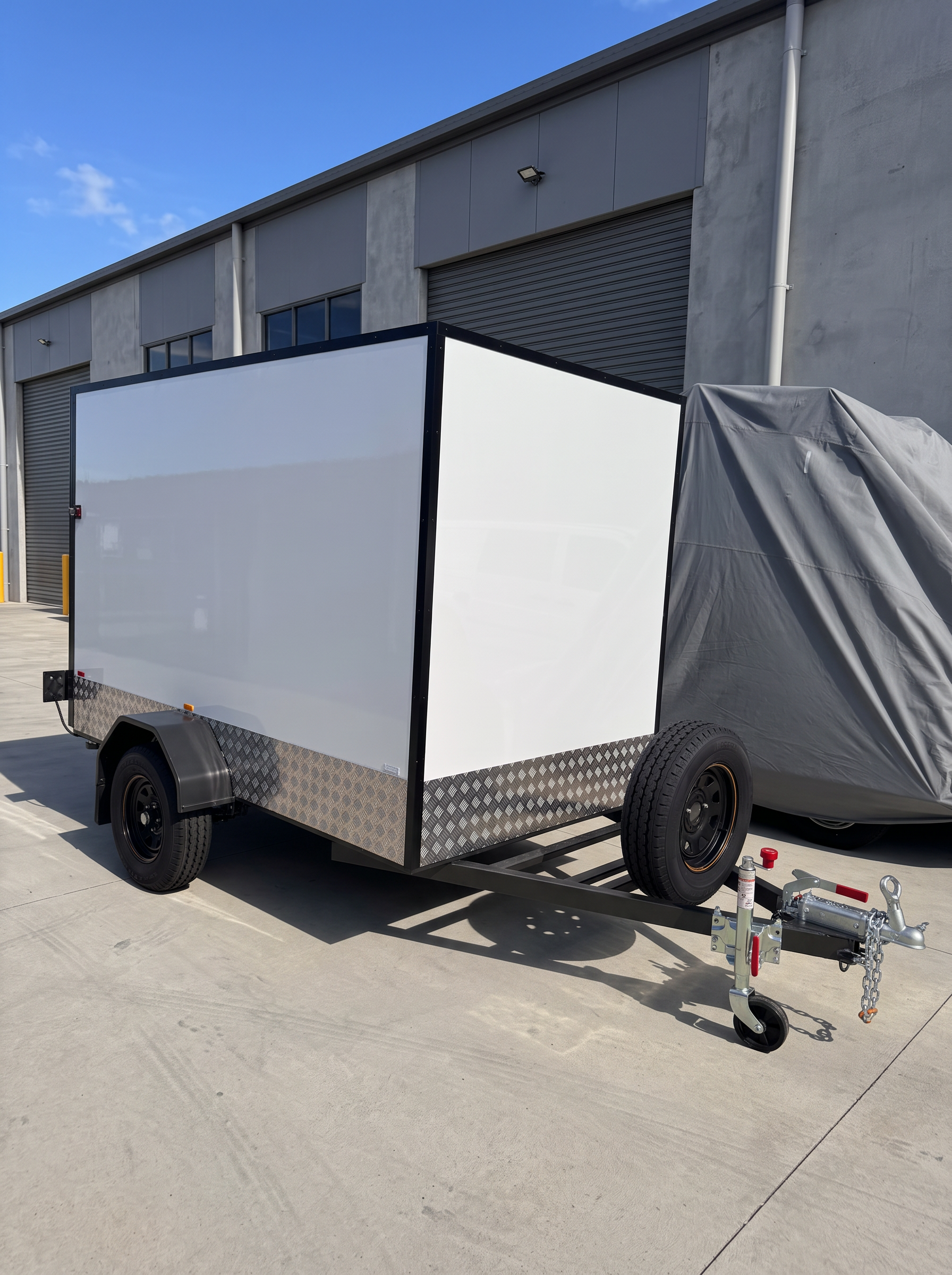 MotoCampers 003 single axle enclosed trailer front three-quarter view in a sealed yard
