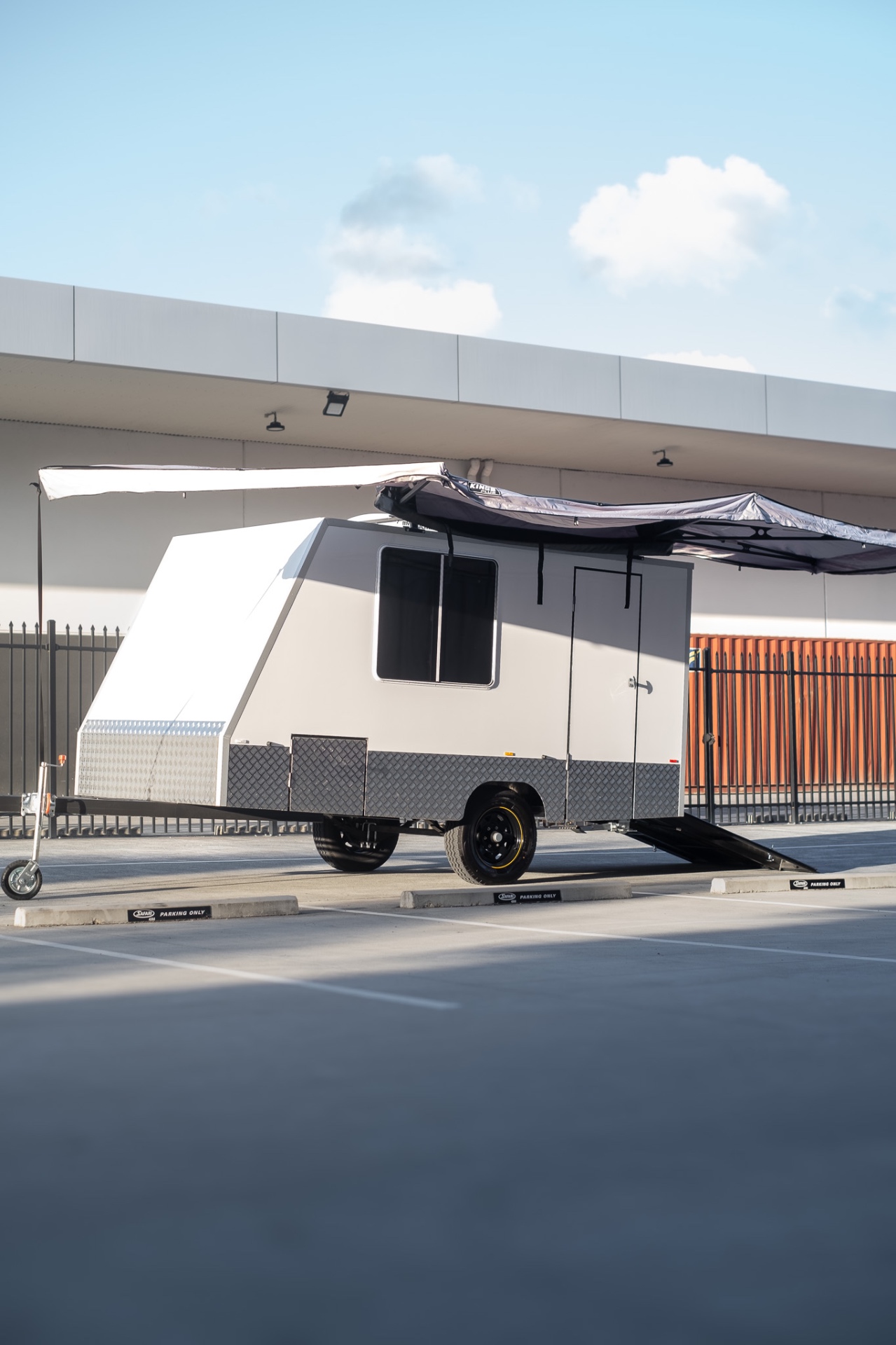 MotoCampers 001 enclosed camper trailer parked with awning and ramp set up