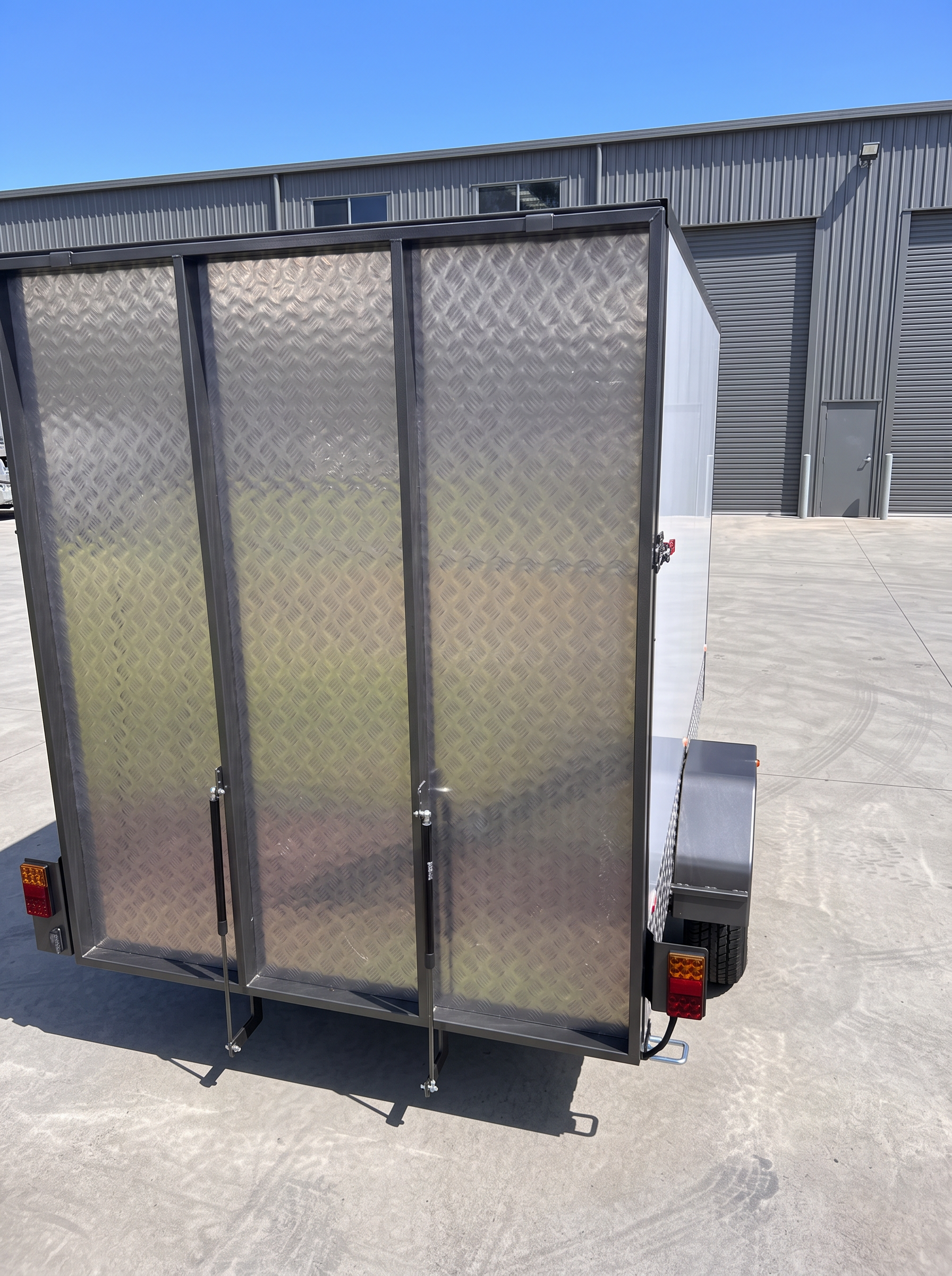 MotoCampers 003 with three gas-strut checkerplate gullwing panels open along the side
