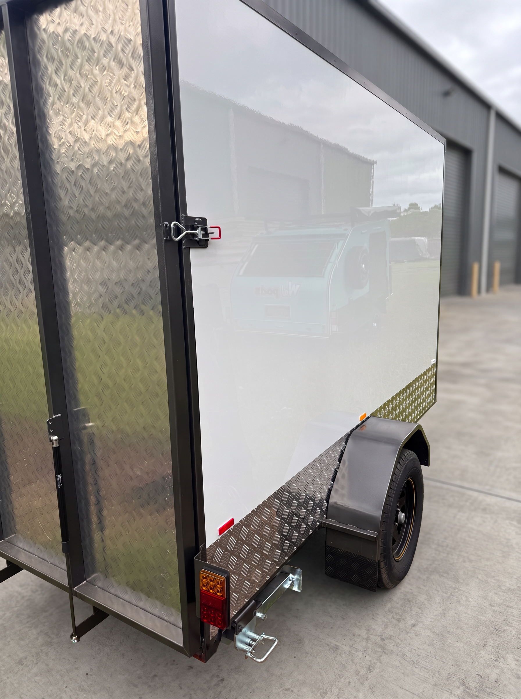 Close view of the MotoCampers 003 side door latch, gas struts and LED tail light