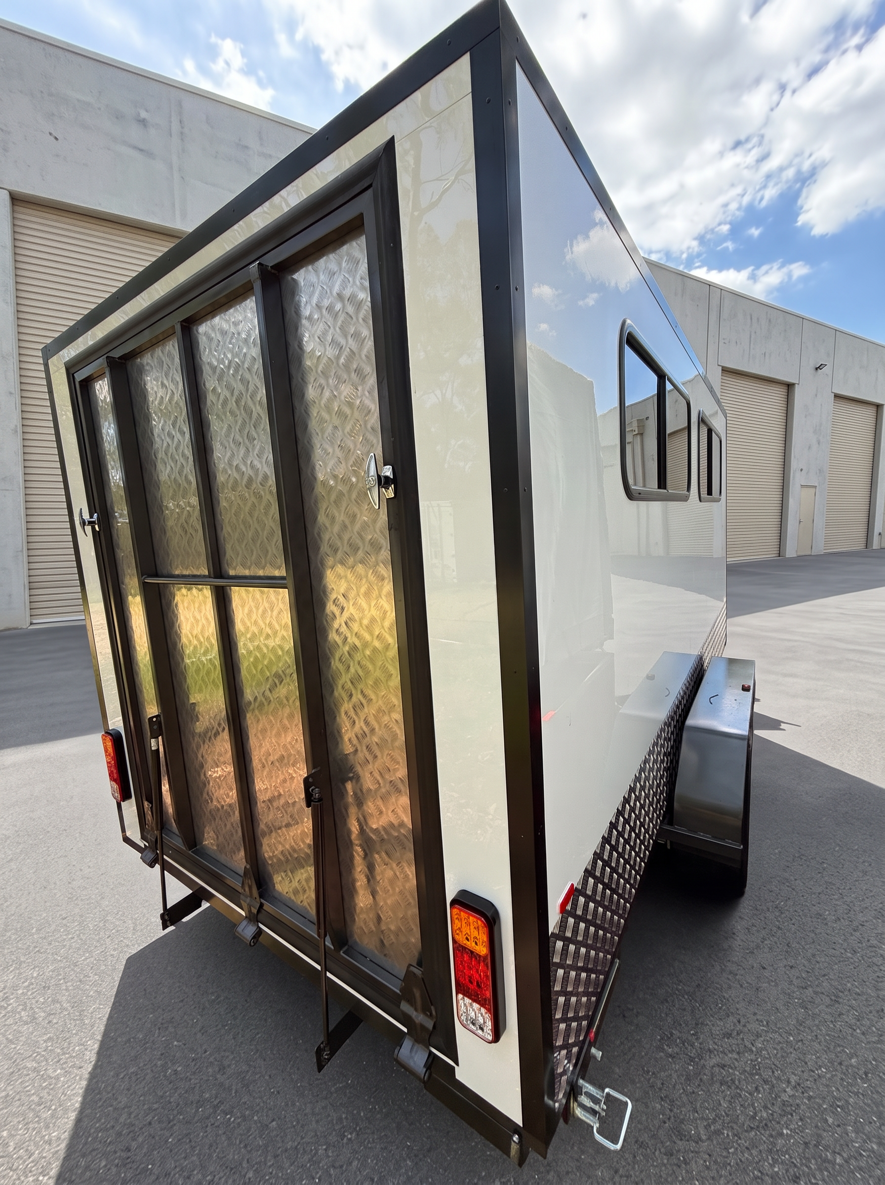 Rear checkerplate barn doors of the MotoCampers 002 enclosed trailer with LED tail lights